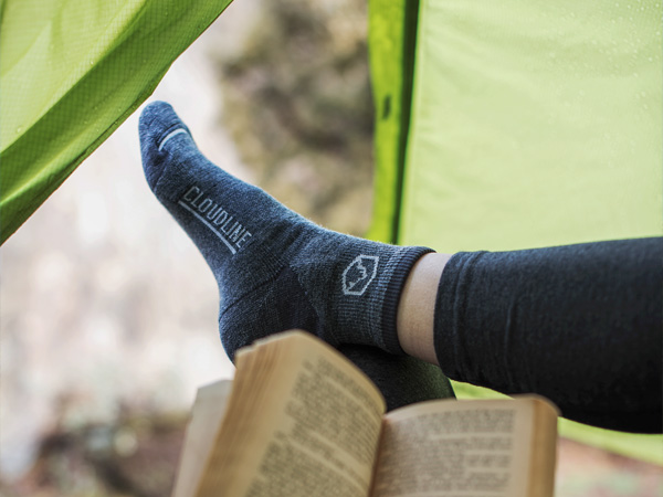 Backpacker reading in tent wearing Cloudline socks