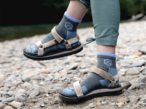 Hiker sitting near river wearing Cloudline socks