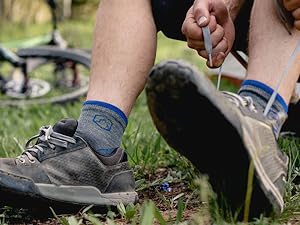 Mountain biker wearing Cloudline socks tying shoes with bike in background