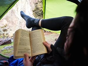 Women sitting in tent reading wearing Cloudline socks