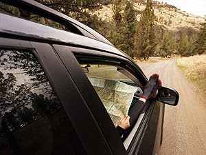 Hiker showing cloudline socks checking map on backcountry road to trail head