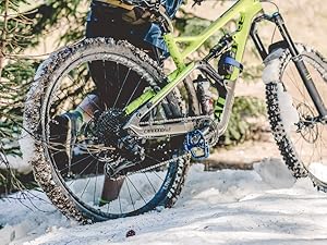 Mountain Biker walking bike through snowy section of trail wearing Cloudline socks